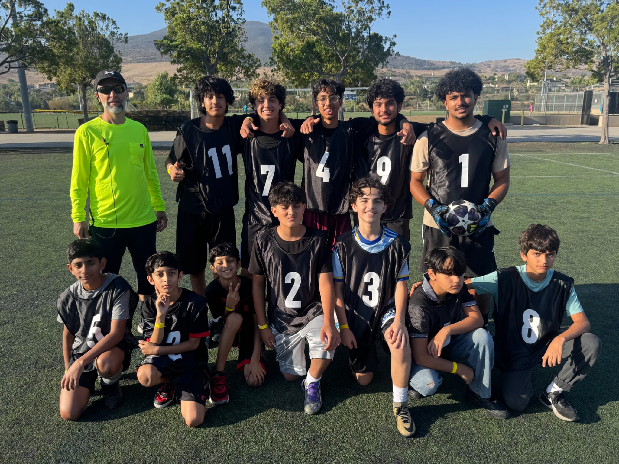 Youth soccer team in black training bibs with their coach